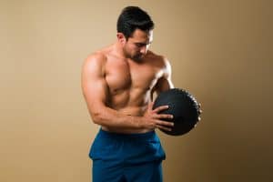 Muscular man exercising using a slam ball